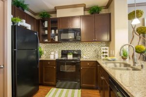 A modern kitchen with sleek black appliances and elegant granite counter tops, found in luxurious apartments for rent in The Woodlands, TX.