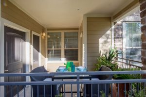 An inviting balcony adorned with a table and chairs, perfect for relaxing in your new Woodlands TX apartment.