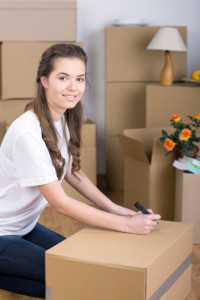 A woman sitting on the floor in front of moving boxes in Apartments in The Woodlands, TX.